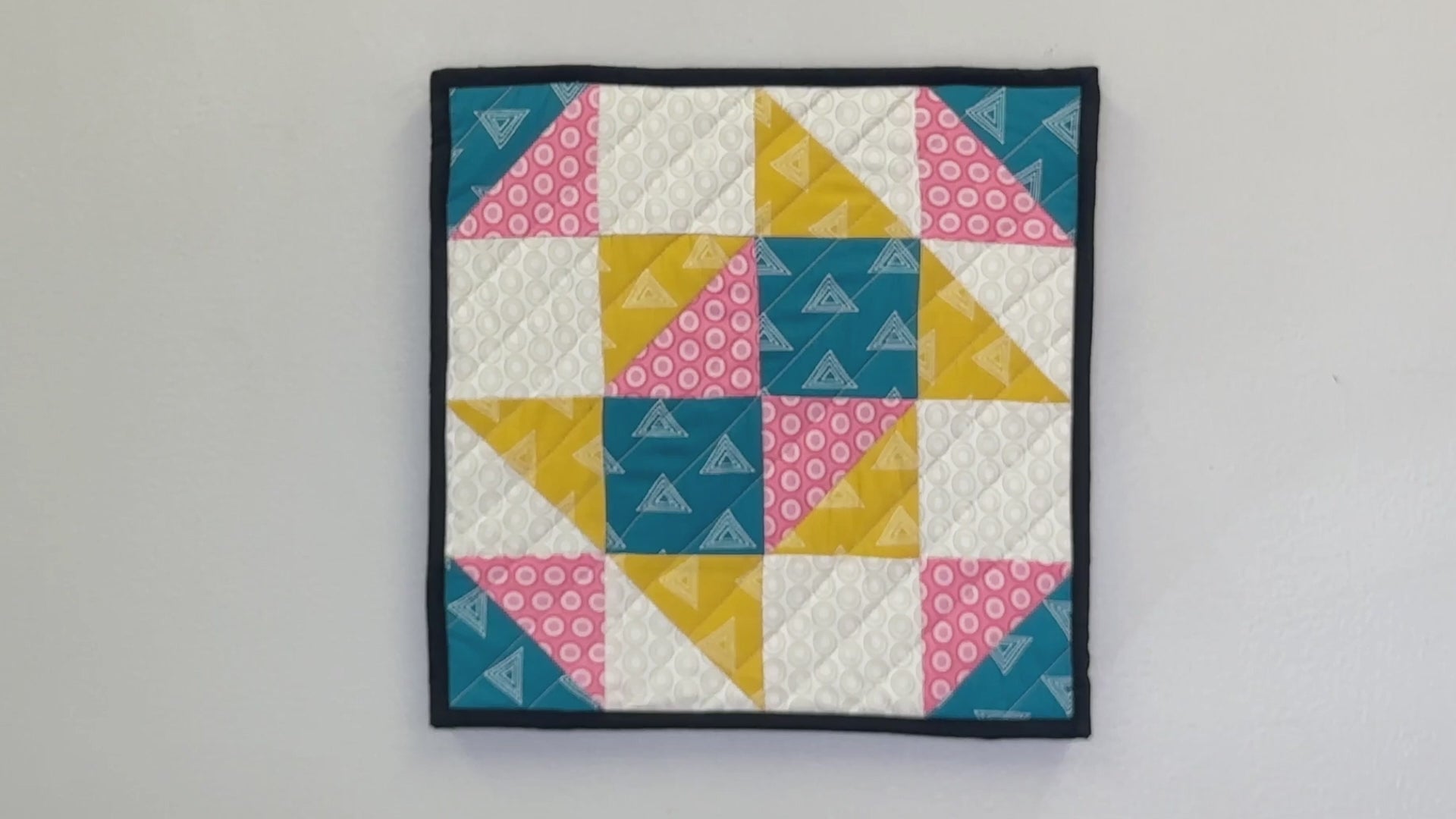 Load video: Demonstration of Sew Much Studio interchangeable quilted wall art being removed from and placed onto a reusable stretched canvas.